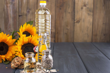Sunflower oil and large yellow flowers. Oil in the bottle. A wooden background, seeds and a biscuit...