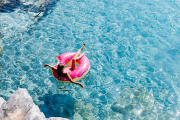 A Woman Floating on Doughnut Ring on Turquoise Sea