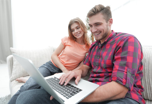 Happy modern couple surfing the net and working on laptop at home