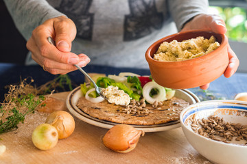 Woman hands holds and spreads dip sauce on garlic naan bread with butter, vegetables salad. Traditional Indian asian plain flatbread made with whole wheat flour. Raw vegan vegetarian healthy food