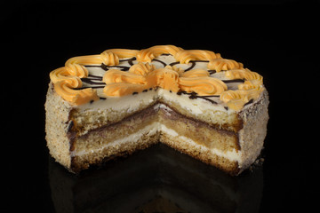 Chunk of chocolate cake decorated with oil cream on a black background