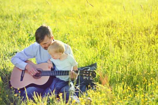 Father teaching his son to play guitar outdoor. Time together dad and son. Copy space