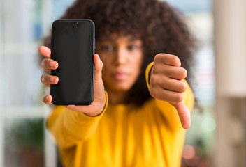 African american woman using smartphone with angry face, negative sign showing dislike with thumbs...