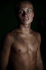 Young guy on a dark background.A strong athletic young man model.Beautiful lips and smile.Beautiful body.