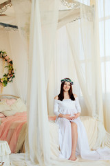 Fototapeta premium Young beautiful girl in the interior of the room, waiting for a miracle, pregnant girl