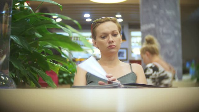 Woman looking at menu in restaurant, turning pages and choosing plates for dinner lunch event dating, 4k, slow motion