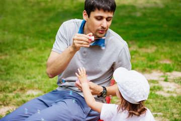 Obraz premium Father and daughter playing with soap bubbles outdoors