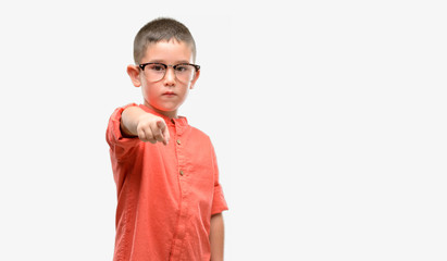 Dark haired little child wearing glasses pointing with finger to the camera and to you, hand sign, positive and confident gesture from the front