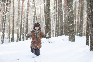 Fototapeta na wymiar A boy in a hat with a fur hat in a winter forest