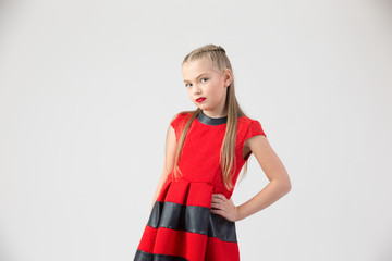 A teenaged blond girl in a red dress and brightly red lips on a white background