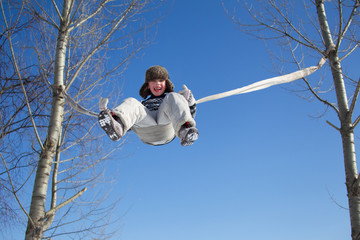 A little boy is riding a rope swing on a winter day high