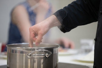 Saucepot with hot water and steam.The cook is measuring the temperature of the finger