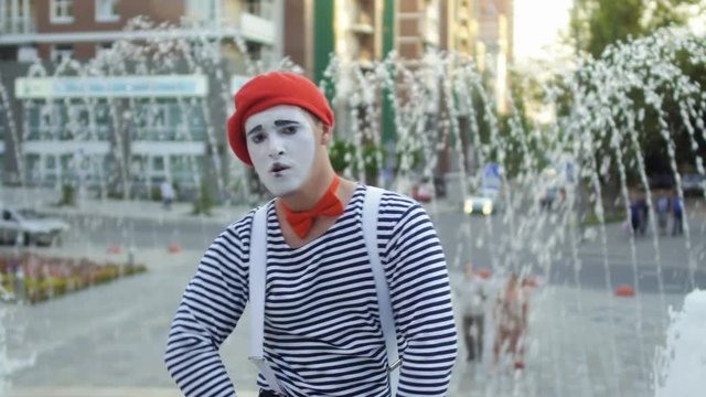 Funny mime wearing red beret and stripped shirt has fun on camera