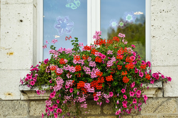 Fototapeta na wymiar Typical Window decorated Pink and Red Flowers in La Bourboule in Auvergne,France