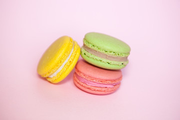 Pink ynd yellow and green french macaroon biscuits on pastel background