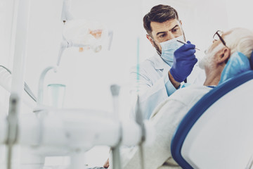Working atmosphere. Professional practitioner using sterile instruments while doing teeth checkup