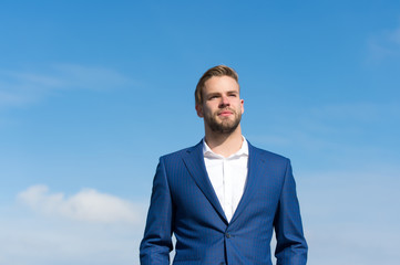 Businessman successful entrepreneur in suit walks outdoor sunny day, sky background. Man confident...