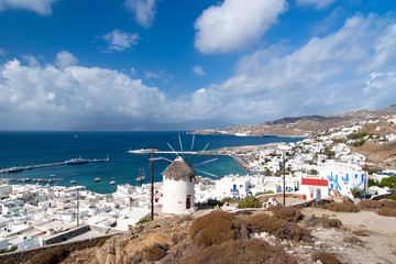Seascape from Mykonos, Greece. Village windmill on mountain landscape by blue sea. White houses on cloudy sky with nice architecture. Wanderlust and travel. Summer vacation on mediterranean island