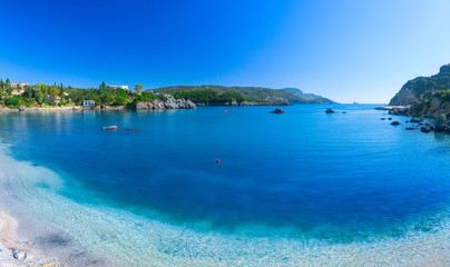 Beautiful summer panoramic seascape. View of Paleokastritsa famous beach in close bay with crystal clear azure water on Corfu island, Ionian archipelago, Greece.