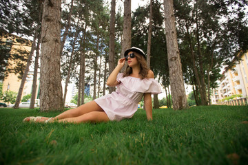 Obraz premium Beautiful girl indress and hat in the park. Green grass and sunny. Background of trees