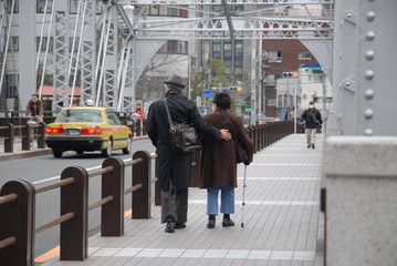 高齢者　後ろ姿　シニア　シニア世代　二人　２人　ふたり　夫婦　橋を渡る　橋　杖　歩道　歩く　散歩　街　町　冬　秋　支え合い　助け合う　サポート　仲の良い　優しさ　優しい　思いやり　横　後　風景　背中