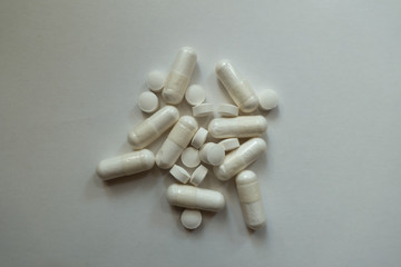 Top view of heap of white magnesium citrate capsules and vitamin K2 tablets