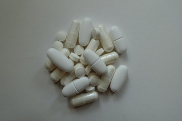 Top view of heap of white magnesium citrate capsules, calcium citrate caplets and vitamin K2 tablets