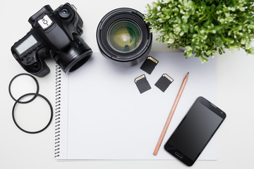 photographer's workplace - camera, photography equipment, smart phone and notepad with pen