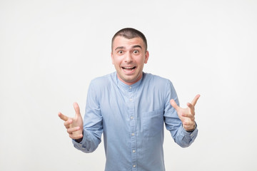 Fototapeta premium young hispanic man in blue shirt celebrating victory of his team over gray background
