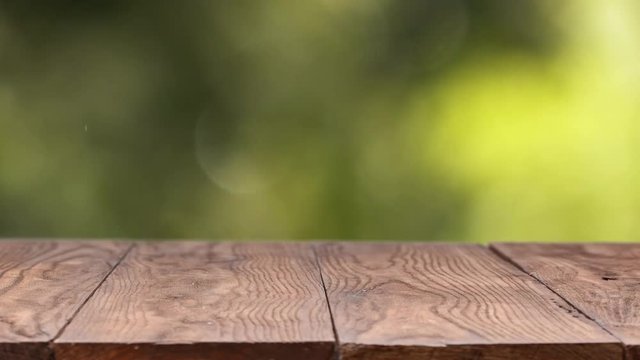 Green Leaves in the wind, a natural blurred background with a wooden old stationary table on a summer sunny day. Slow motion, 1080p full HD video
