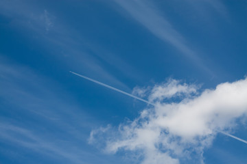 Naklejka na ściany i meble Aircraft trail of jet against the wide blue sky width clouds