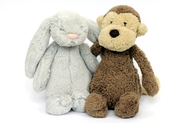 A grey fluffy rabbit soft toy and brown fluffy monkey soft toy