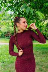 Beautiful young woman with long braid and natural cherry earrings.
