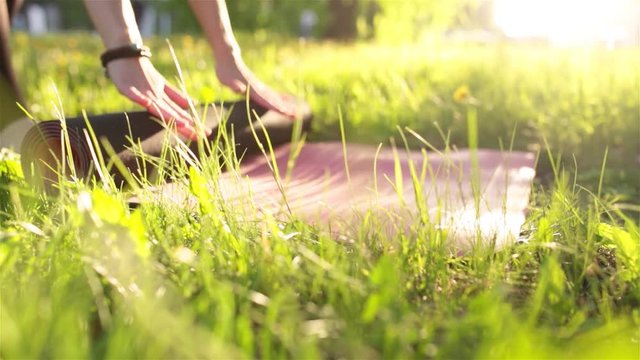 Young sportive woman doing yoga, pilates and exercising in the park on beautiful day at sunset on green grass. Healthy lifestyle concept