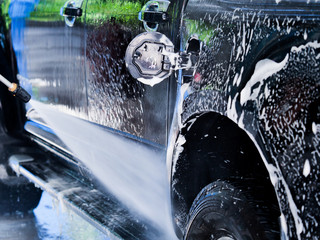 Close up man hands  worker washing car's alloy wheels at garage