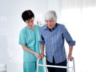Nurse helping Elderly Woman Using Walking Frame.
