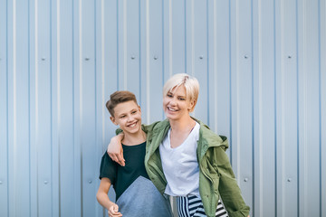 beautiful happy stylish mother and son laughing and embracing on street