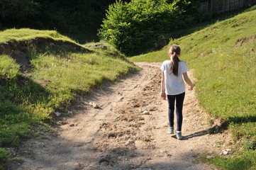 Child, blonde girl with long hair, descending down the path in the valley