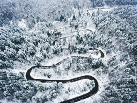 Winter curved winding road in the forest covered in snow