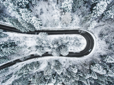 White car passing on an extreme winding road in wintertime