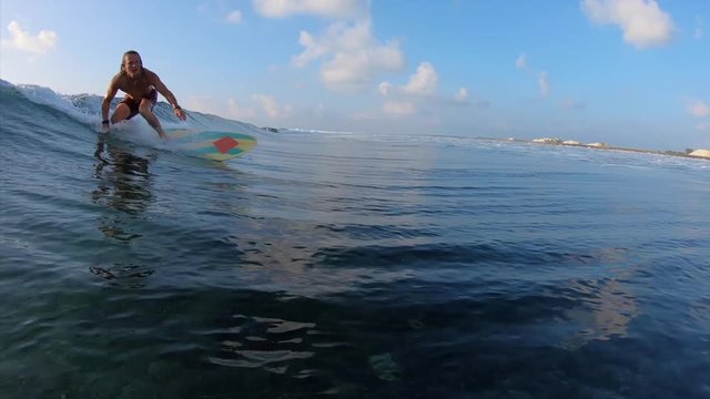 Amatuer surfer rides the tropical wave. Surf spot Jailbreaks near the island of Himmafushi, Maldives