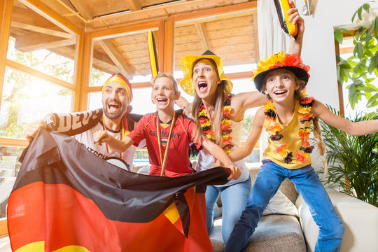 Happy family cheering for the German soccer team in front of TV