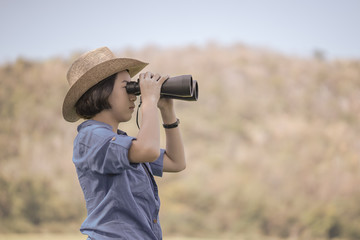 Woman wear hat and hold binocular in grass field