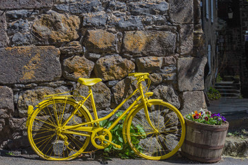 bicyclette jaune posée contre un mur en pierre