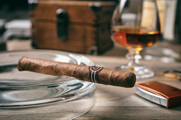 Cuban cigar in an ashtray on wooden desk
