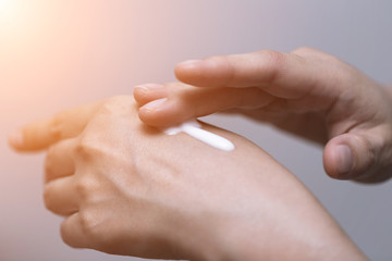 Young woman is using sunblock lotion on her hand, beauty concept.