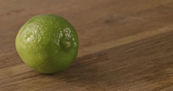 Two limes with drops of water fall on a wooden table. Slow motion 2k video shooted on 240 fps