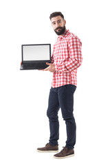 Cool bearded hipster guy in smart casual clothes showing blank laptop monitor. Full length isolated on white background. 