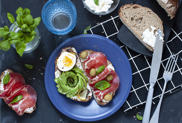 Avocado and meat toasts flat lay on the dark background. Breakfast top view.