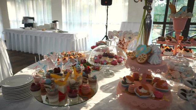 Overview of the wedding candy bar reception full of different colorful and tasty cookies, candies, cakes, cake-pops and macarons. Wedding ceremony. Birthday celebration.
